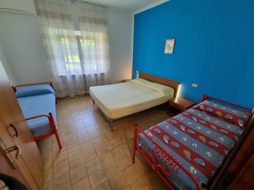 a bedroom with two beds and a blue wall at Appartamento Mario in Sirolo