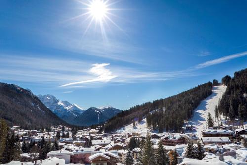 a ski resort in the snow with the sun in the sky at Cristal Palace Hotel in Madonna di Campiglio