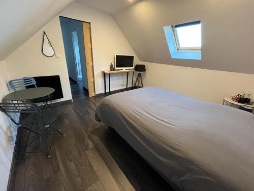 1 dormitorio con cama, mesa y TV en Maison chiron en Montreuil-sur-Maine