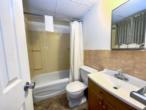a bathroom with a sink and a toilet and a bath tub at Capone's Hideaway Motel in Moose Jaw
