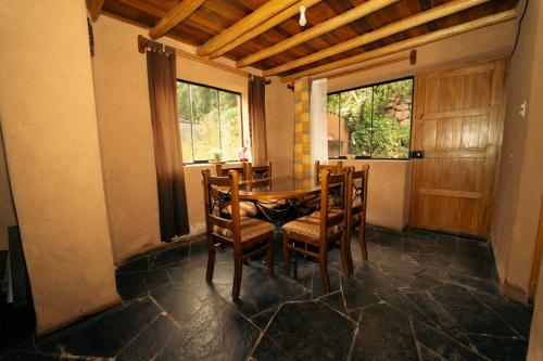 a dining room with a table and chairs and windows at Casa cabaña privada en el Valle Sagrado Urubamba in Urubamba
