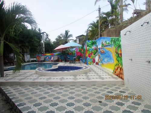 a pool with a patio with a table and an umbrella at Hostal Recuerdos del Tayrona in El Zaino