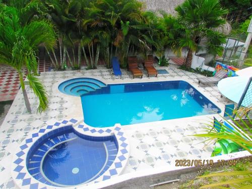 a swimming pool in a backyard with palm trees at Hostal Recuerdos del Tayrona in El Zaino