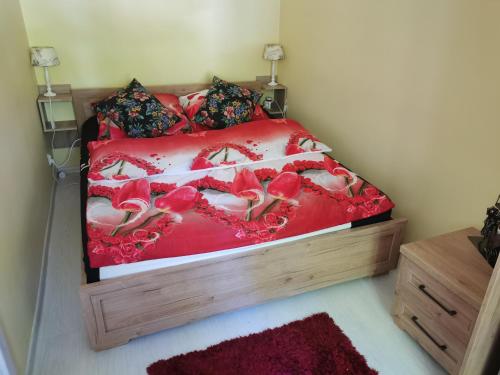 een slaapkamer met een bed met rode lakens en rode rozen bij Mieszkanie dwupokojowe na wsi w domu dwurodzinnym in Postomino