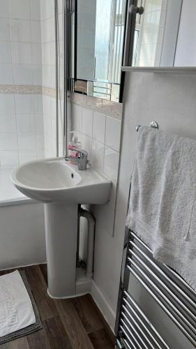 a white bathroom with a sink and a bath tub at Flat 1 in Hendon