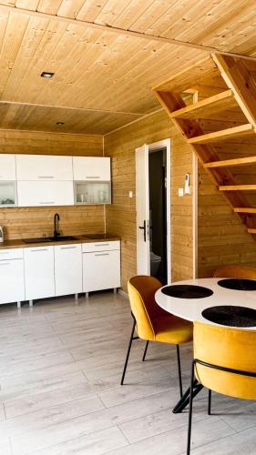 a kitchen with white cabinets and a table and chairs at Domki Kunice in Kunice