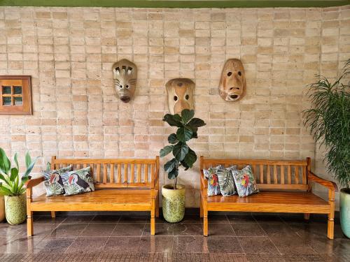 two benches sitting next to a wall with face heads at Hotel Pousada Santa Rita in Ribeirão Preto