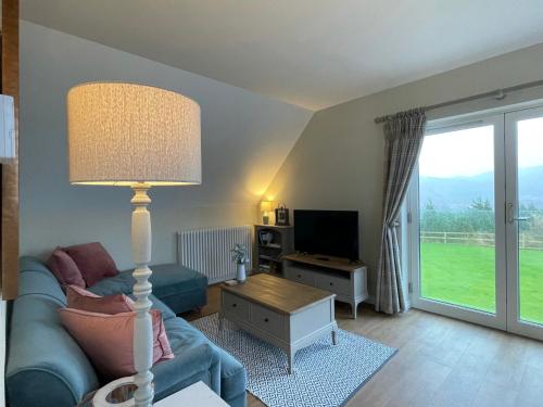 a living room with a blue couch and a lamp at Little Thistle Apartment in Whitebridge
