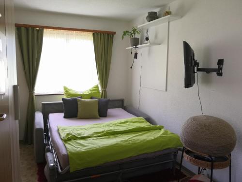 Apartment am Birkenweg : غرفة نوم بسرير وملاءات خضراء ونافذة
