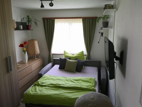 una camera da letto con letto con lenzuola verdi e finestra di Apartment am Birkenweg 