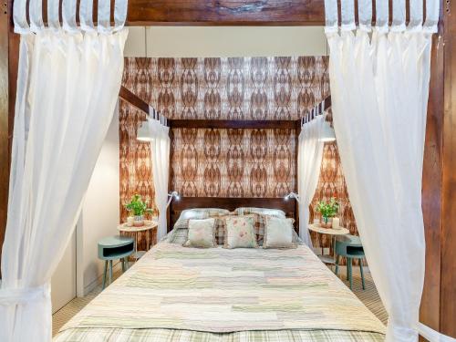 a bedroom with a bed with curtains and two tables at The Stables in Longridge