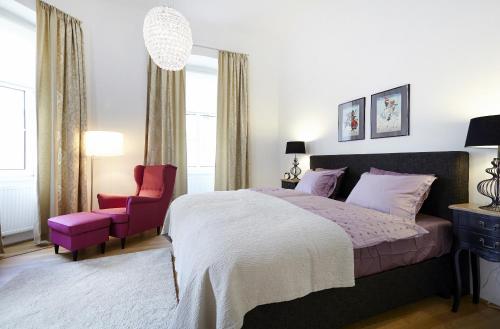 a bedroom with a large bed and a pink chair at Apartment Theresiengasse in Vienna