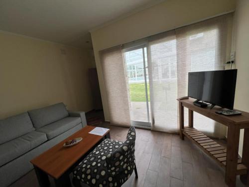 a living room with a couch and a table and a tv at Tandil del Lago in Tandil