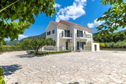 a large white house with a stone driveway at Arte villa Margarita apartment in Sami