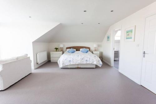 a white bedroom with a bed with blue pillows at 2100 Sq Ft Beach House with large garden in Earnley