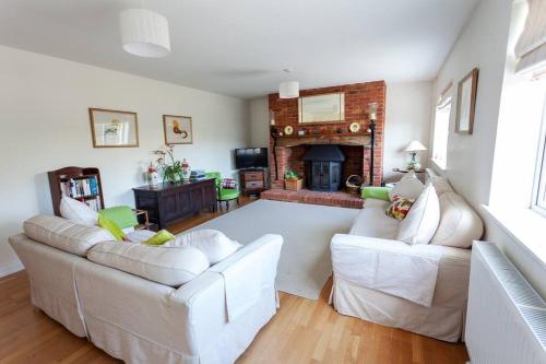 a living room with two white couches and a fireplace at 2100 Sq Ft Beach House with large garden in Earnley