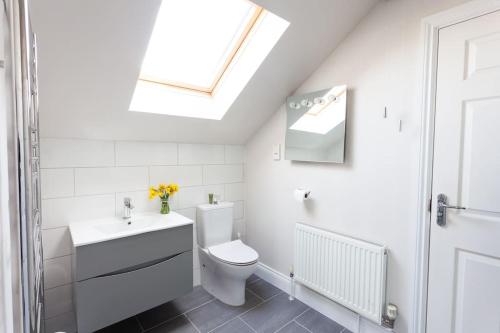 a bathroom with a toilet and a sink and a skylight at 2100 Sq Ft Beach House with large garden in Earnley