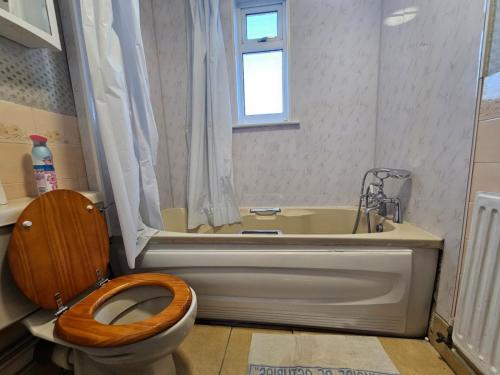 a bathroom with a toilet and a tub with a wooden toilet seat at Mo's home in Tilbury
