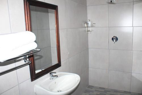 a white bathroom with a sink and a mirror at Kekeli B&B in Vryheid
