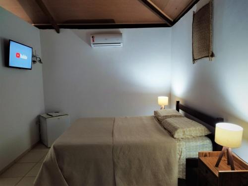 a bedroom with two beds and a tv on the wall at Bangalô Panorâmica in Conde