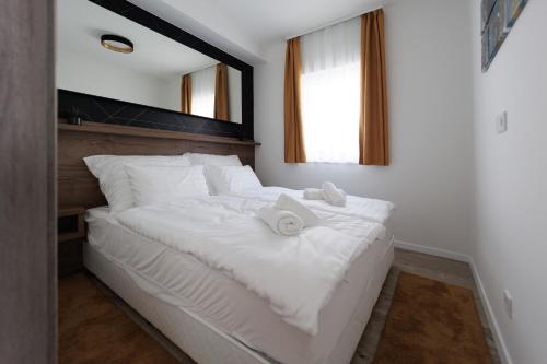 Villa Bauhaus Gold في سيوفوك: سرير ابيض عليه مناشف في غرفة النوم