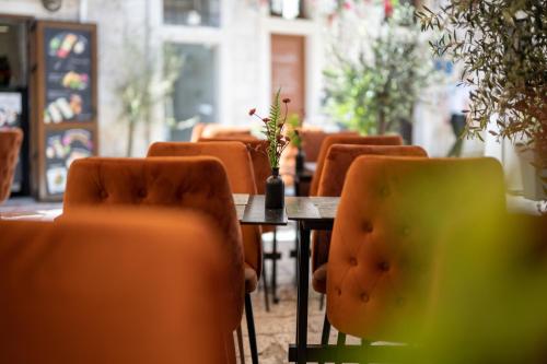 a table with orange chairs and a table with a vase on it at Luxury Rooms "Kaleta" in Trogir