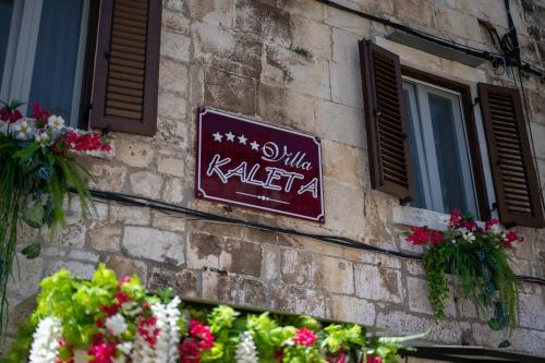 a sign on the side of a building with flowers at Luxury Rooms "Kaleta" in Trogir