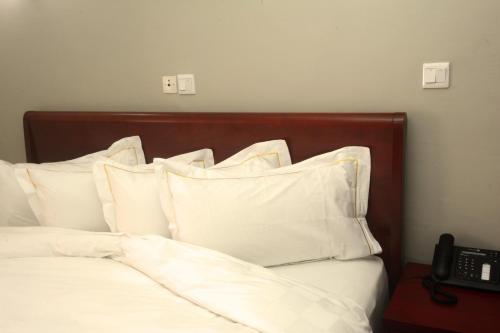 a bedroom with a bed with white pillows and a telephone at Hotel La Falaise Yaounde in Yaoundé