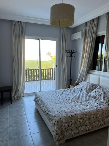 a bedroom with a bed and a large window at Maison de Campagne in Dar SaÃ¯d Ben Hajj