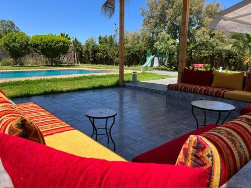 une terrasse avec des canapés et des tables à côté d'une piscine dans l'établissement Maison de Campagne, à Dar SaÃ¯d Ben Hajj