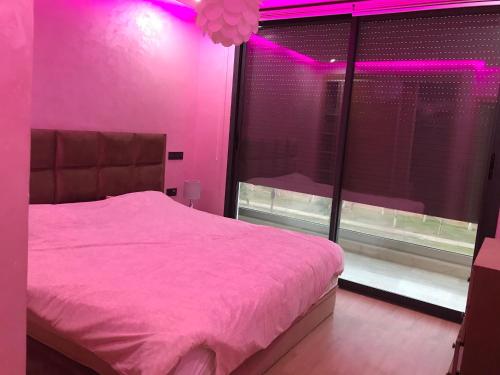 Un dormitorio rosa con una cama y una ventana con luces rosas. en Résidence Agadir bay 2, en Agadir