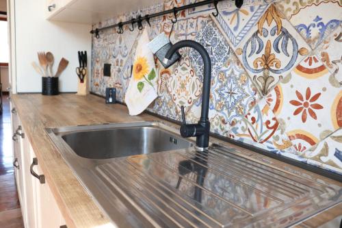 - une cuisine avec un évier et un mur en carrelage dans l'établissement Casa Basso, à Loano