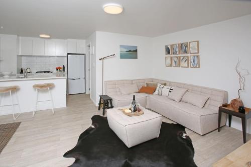 ein Wohnzimmer mit einem Sofa und einer Küche in der Unterkunft Garden Apartment in Matakana