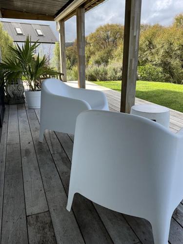 two white benches sitting on a wooden deck at Garden Apartment in Matakana