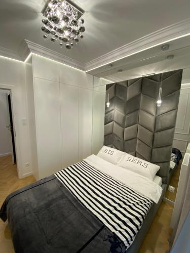 1 dormitorio con 1 cama en una habitación con lámpara de araña en Apartamenty Jagiellońskie Jurowiecka 15, en Białystok