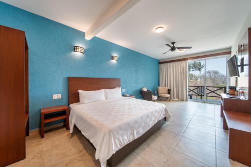 サンタ・クルス・ウアトゥルコにあるVillas Coral Huatulcoの青い壁のベッドルーム1室(ベッド1台付)