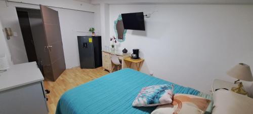 a small bedroom with a blue bed and a kitchen at Habitaciones Narvarte Del Valle in Mexico City