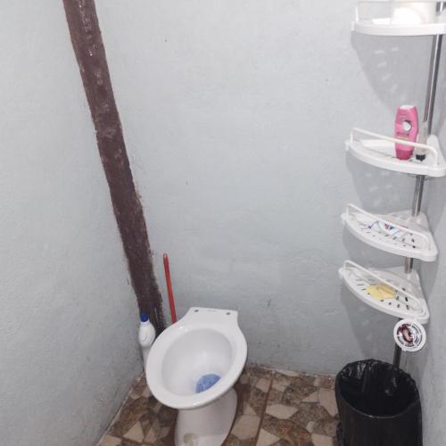 a bathroom with a toilet and two shelves on the wall at Klay's tiny home in San Isidro