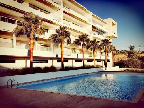 a building with palm trees and a swimming pool at Lujoso aprtamento cap tingis playa tanger in Tangier