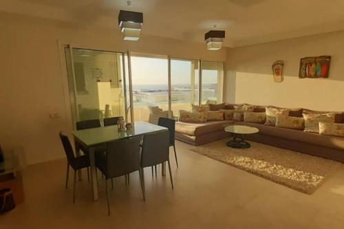 a living room with a couch and a table and chairs at Lujoso aprtamento cap tingis playa tanger in Tangier