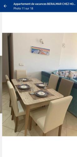 a dining room table with white chairs and a wooden table and chairsktop at Appartement de vacances BERALMAR CHEZ HOUDA in Asilah