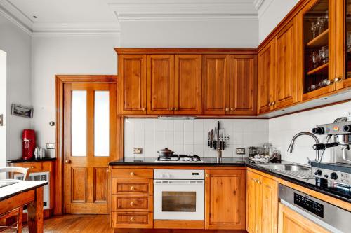 cocina con armarios de madera y horno con fogones en The Glebe Cottage, en Hobart