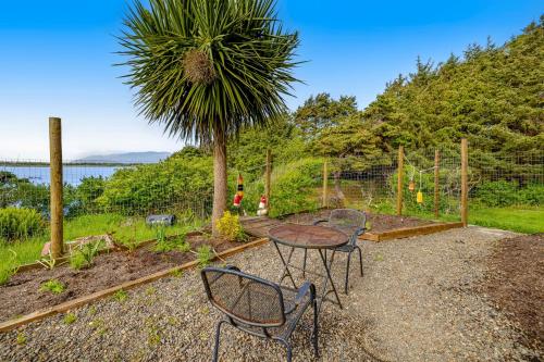 a table and chairs in a garden with a palm tree at Escape to the Cape in Tillamook