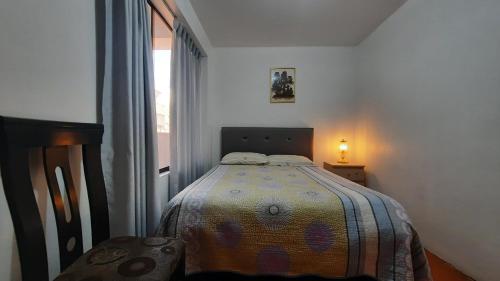 um quarto com uma cama com um cobertor em DEPARTAMENTO CÉNTRICO , CÓMODO Y ECONÓMICO EN CUSCO em Cusco