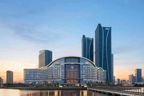 a large building in front of a city with tall buildings at Sheraton Rizhao Hotel in Rizhao