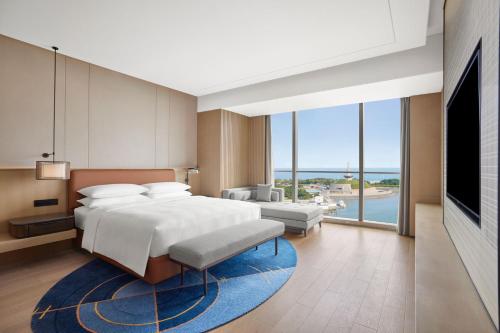 - une chambre avec un grand lit et une grande fenêtre dans l'établissement Sheraton Rizhao Hotel, à Rizhao