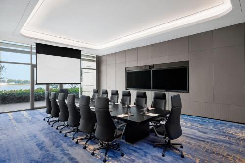 a conference room with a table and chairs and a projection screen at Sheraton Rizhao Hotel in Rizhao