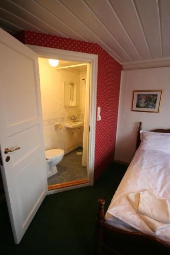 a bedroom with a bed and a bathroom with a tub at Norneshuset Overnatting in Skudeneshavn