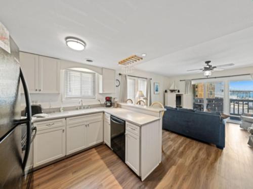 a large kitchen with white cabinets and a living room at Island North 14C - 2nd row stunner! Relax in comfort after your days in the sun condo in Carolina Beach