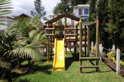 a playground in a yard with a yellow slide at Hotel Las Palmeras Gachancipa in Gachancipá